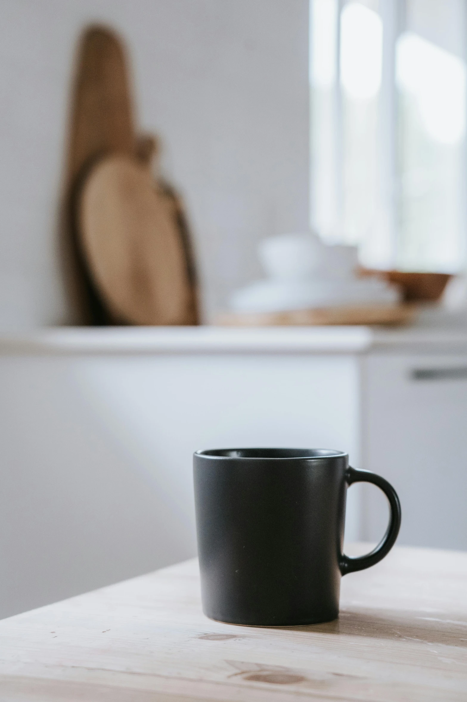 a black coffee cup sitting on top of a wooden table, pexels contest winner, in a kitchen, looking away, set against a white background, detailed product image