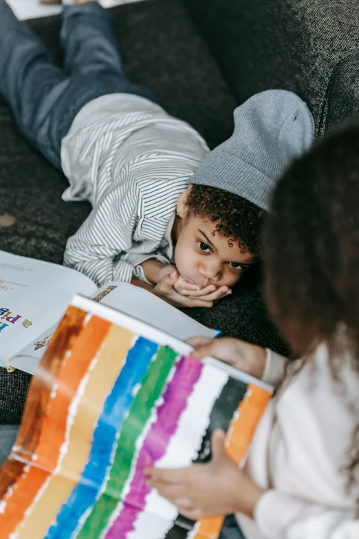 a couple of kids laying on top of a couch, a child's drawing, pexels contest winner, holding a book, lgbt, looking serious, gif