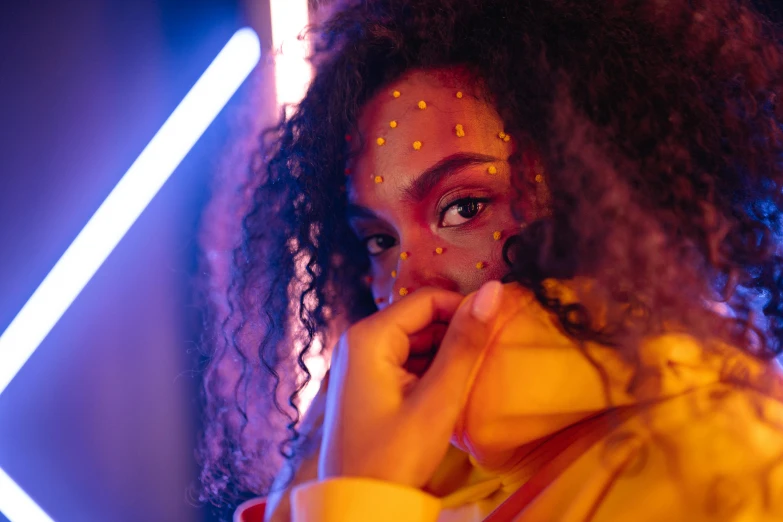 a woman with gold glitter on her face, a picture, by Adam Marczyński, trending on pexels, afrofuturism, orange neon, wearing red and yellow clothes, lights on, sza