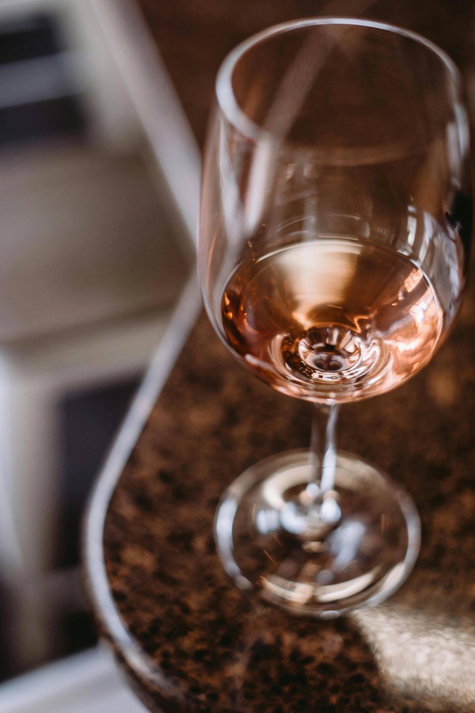 a glass of wine sitting on top of a counter, rose twining, up close, carefully crafted, intimate