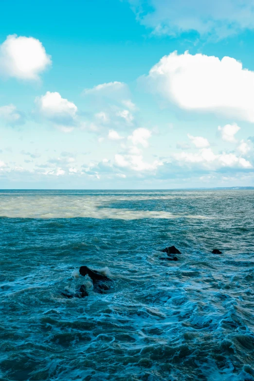 a man riding a surfboard on top of a wave in the ocean, in the ocean, ocean in the distance, floating rocks, rayleigh scattering