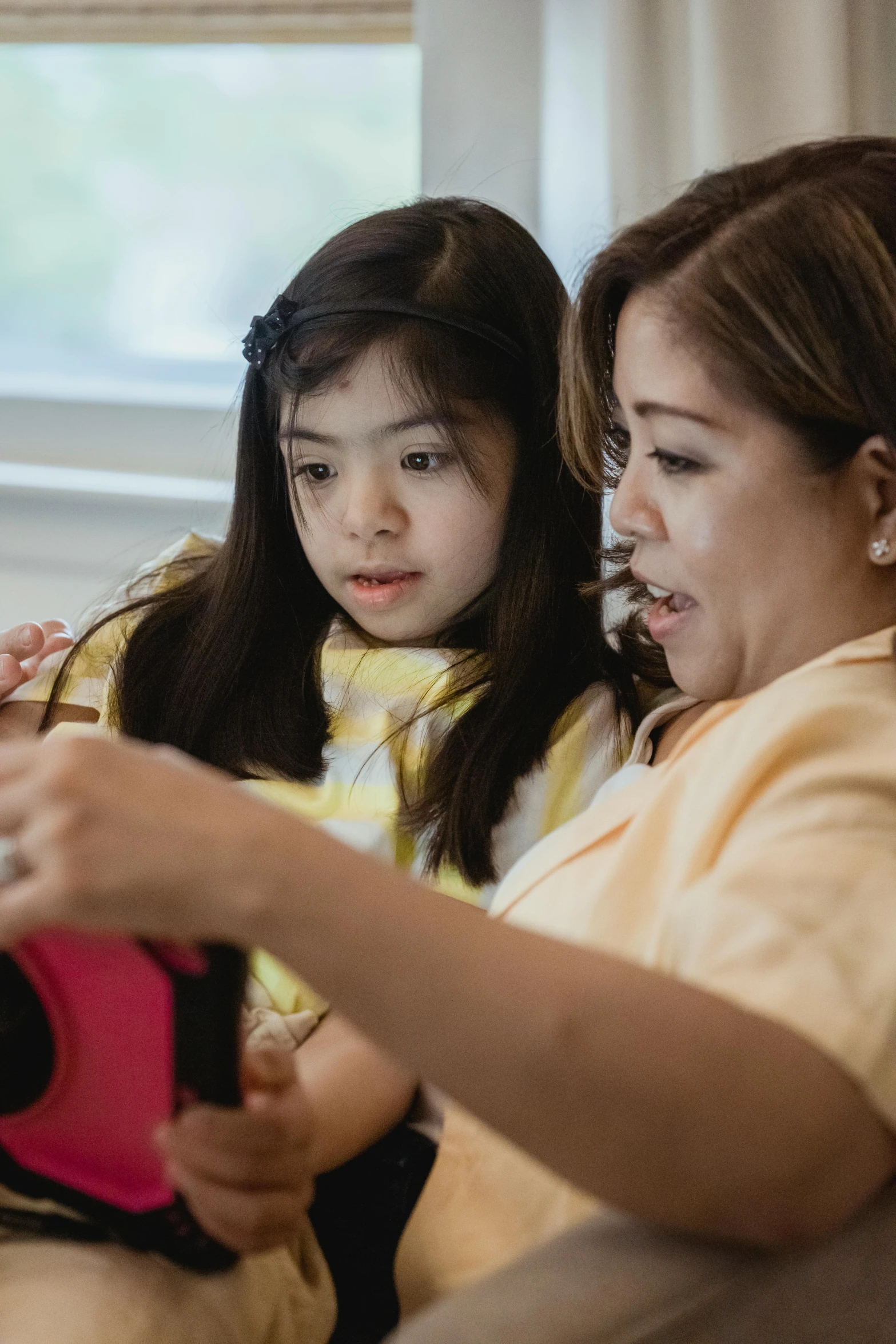 a woman sitting next to a little girl on a couch, by Pablo Carpio, pexels contest winner, integrating with technology, philippines, avatar image, closeup portrait shot