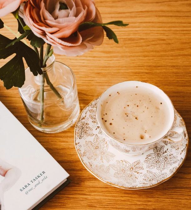 a book sitting on top of a table next to a cup of coffee, by Sara Saftleven, romanticism, beige and gold tones, high quality product image”, blooming, cappuccino