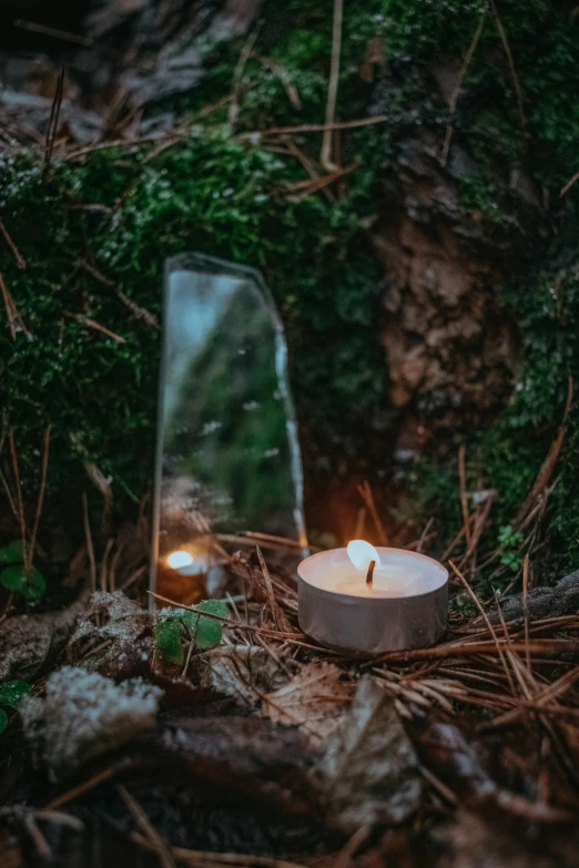 a candle sitting on the ground next to a mirror, unsplash contest winner, land art, forest picnic, glass domes, single light, outdoors