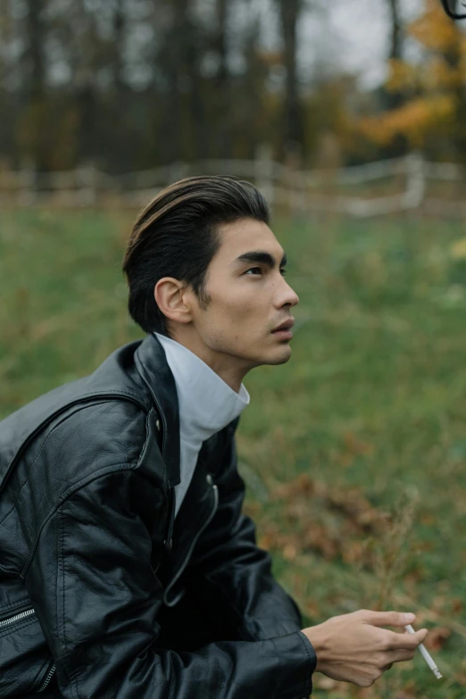 a man in a leather jacket smoking a cigarette, an album cover, inspired by Tadashi Nakayama, trending on pexels, countryside, prominent cheekbones, autumnal, asian descent
