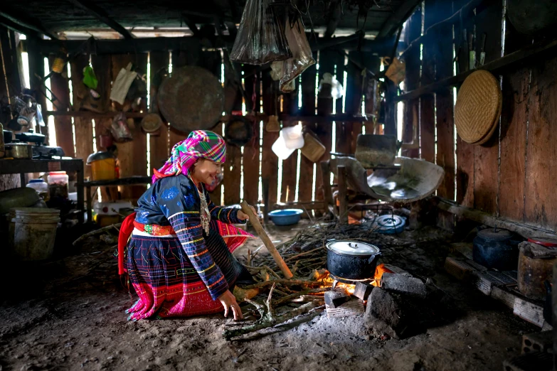 a woman cooking over an open fire in a hut, pexels contest winner, process art, shipibo patterns, wearing authentic attire, vietnam, multicoloured