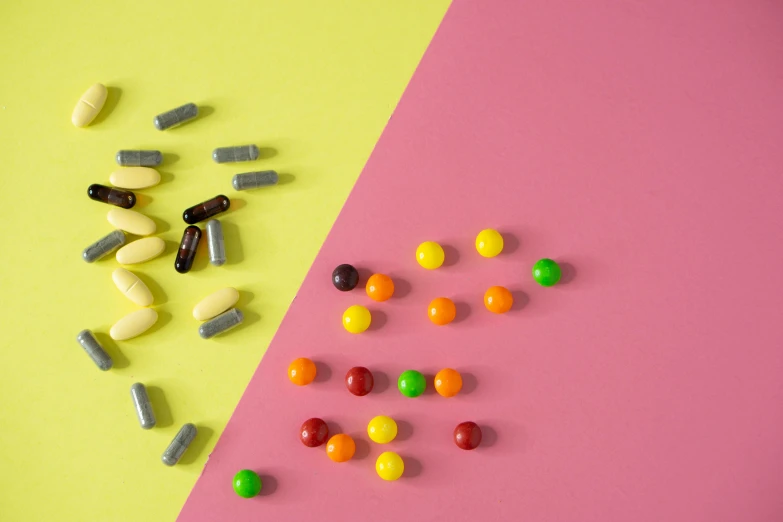 a couple of different colored pills on a pink and yellow background, a still life, inspired by Damien Hirst, trending on pexels, on a gray background, chocolate, rainbow coloured rockets, chartreuse and orange and cyan