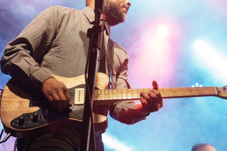 a man playing a guitar in front of a microphone, pexels contest winner, figuration libre, hands on hips, coloured, grey, concert footage