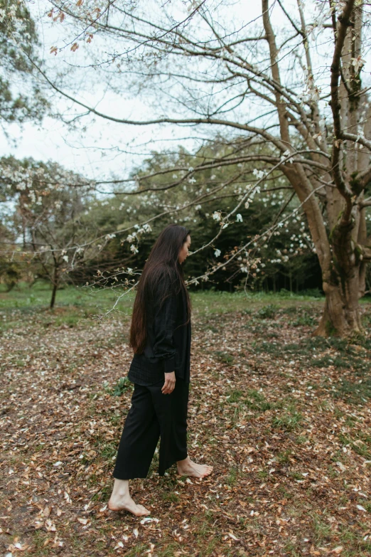 a woman standing in a field with a frisbee in her hand, inspired by Itō Shinsui, unsplash, casual black clothing, blossoms, in the wood, full body photo