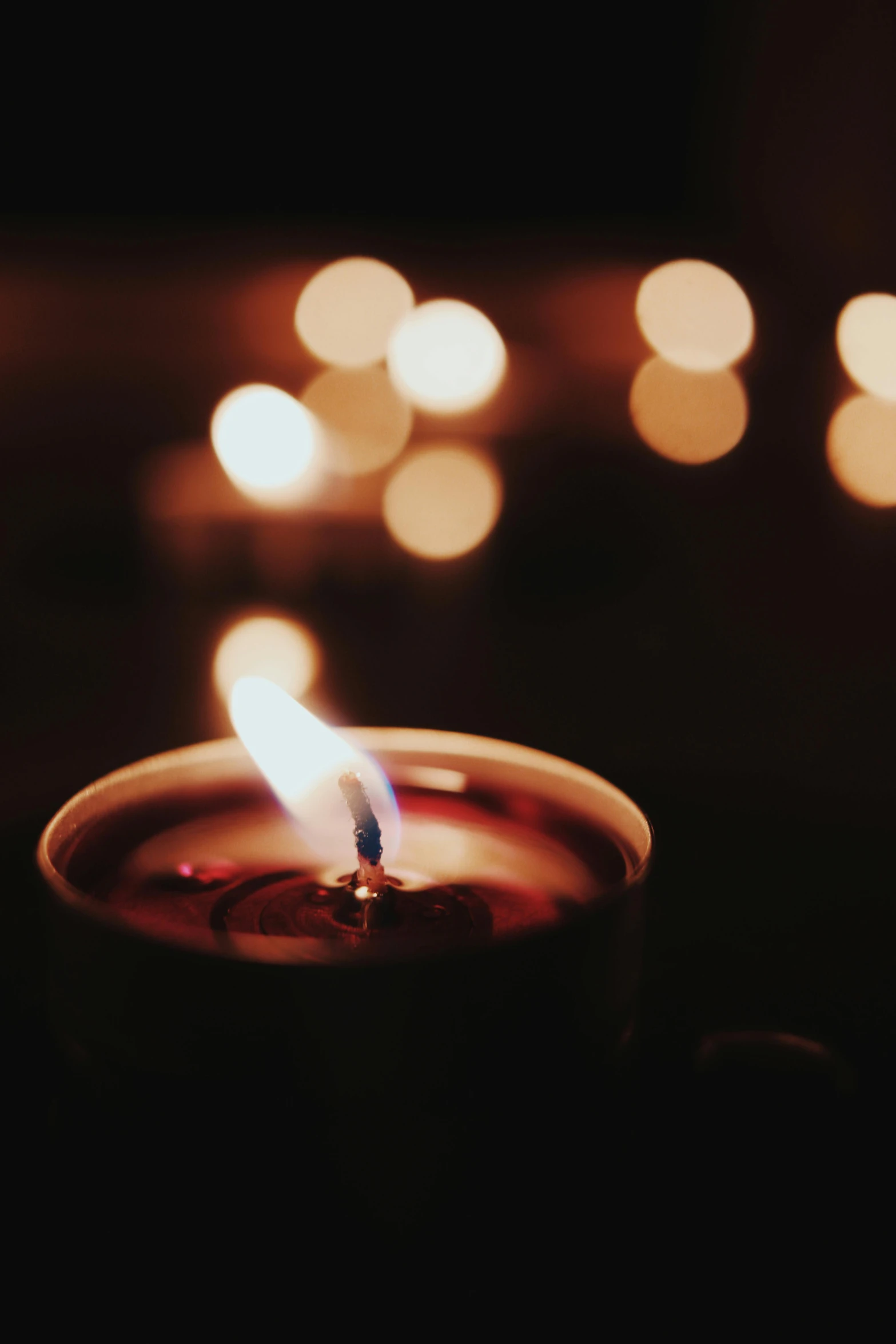 a lit candle sitting on top of a table, light scatter, muted lights, instagram picture, dark. no text