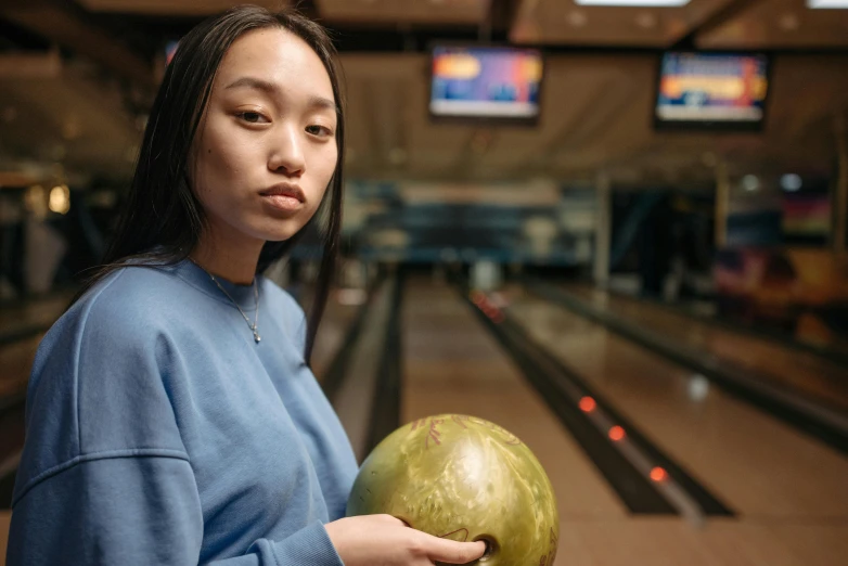 a woman holding a bowling ball in a bowling alley, pexels contest winner, hyperrealism, asian descent, centered in portrait, instagram post, holding a stuff