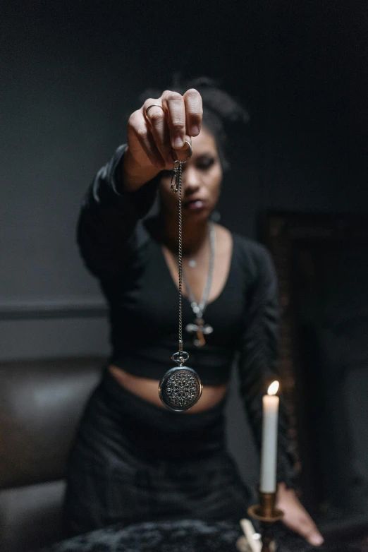 a woman sitting on top of a bed next to a candle, an album cover, trending on pexels, symbolism, occult jewelry, holding a pocket watch, kemetic, profile image