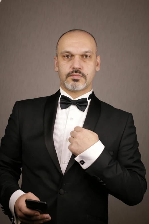 a man in a tuxedo holding a cell phone, an album cover, inspired by Edi Rama, pexels, renaissance, in a fighting stance, vitaliy bondarchuk, headshot profile picture, muscular magician man