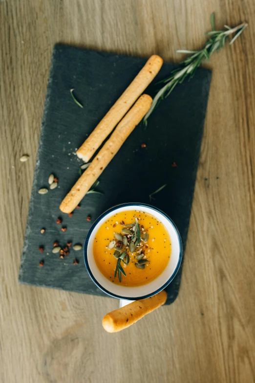 a bowl of soup sitting on top of a cutting board, a picture, caparisons, thumbnail, snacks, ocher details