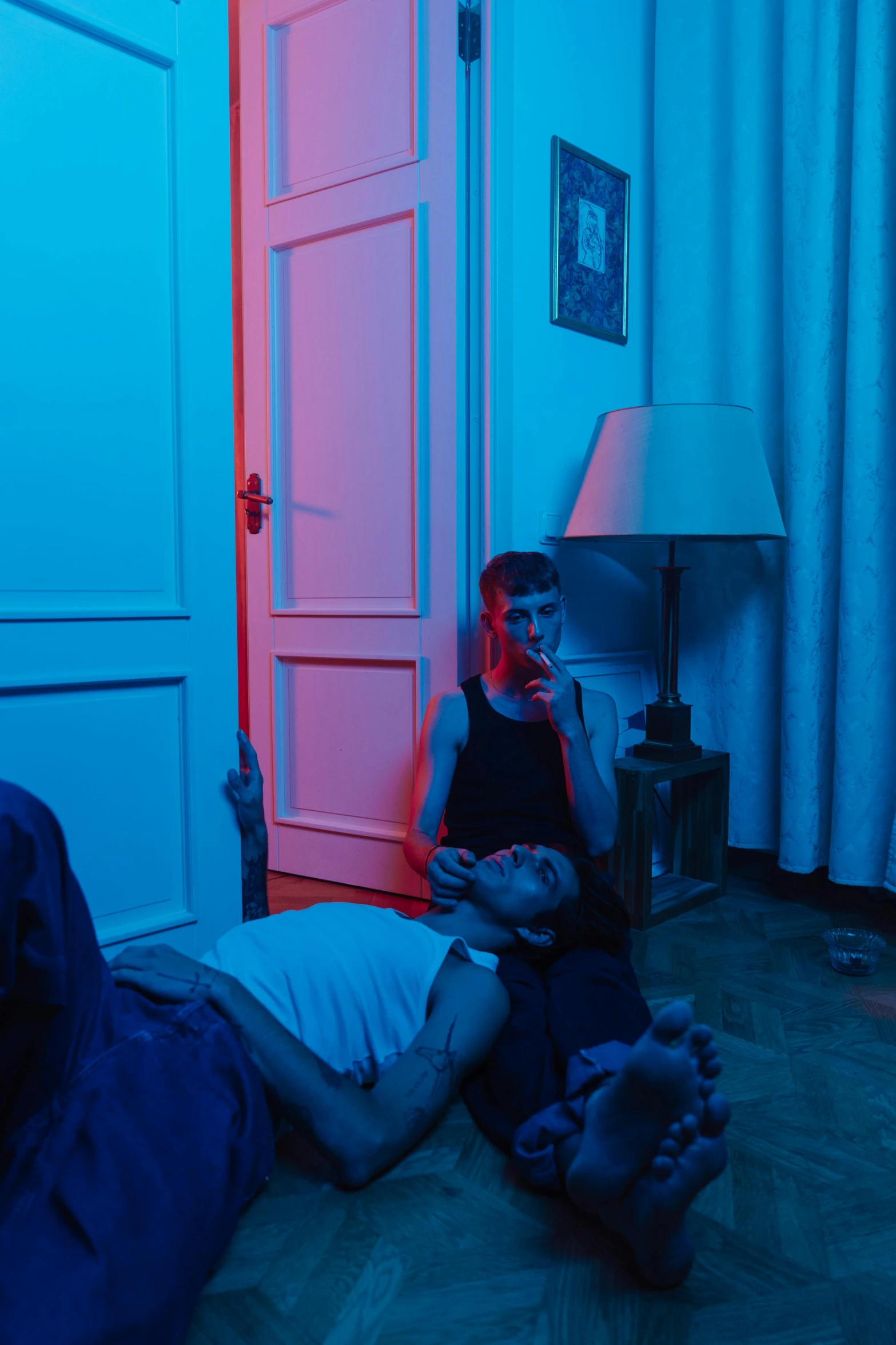 a couple of people laying on the floor in a room, an album cover, inspired by Nan Goldin, pexels contest winner, blue colors with red accents, young handsome pale roma, ( ( ( synthwave ) ) ), leaving a room