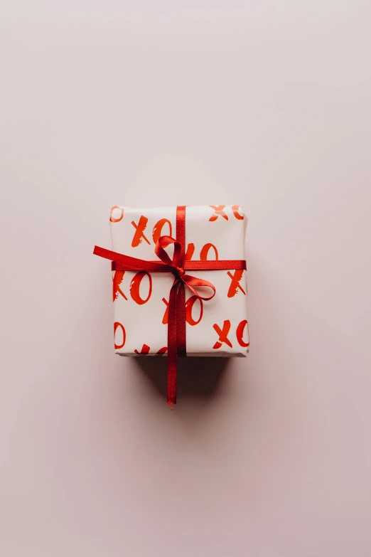 a present wrapped in white paper with red ribbon, by Valentine Hugo, pexels contest winner, pink, 256435456k film, instagram post, on a pale background