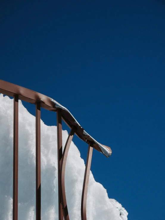 a metal railing with snow on top of it, by Peter Churcher, unsplash, conceptual art, clear blue skies, iceberg, brown, full frame image
