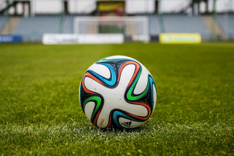 a soccer ball sitting on top of a lush green field, on ground