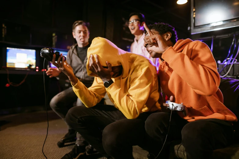 a group of people sitting on a couch playing a video game, pexels contest winner, realism, wearing a yellow hoodie, performing on stage, photograph of three ravers, shot on canon camera