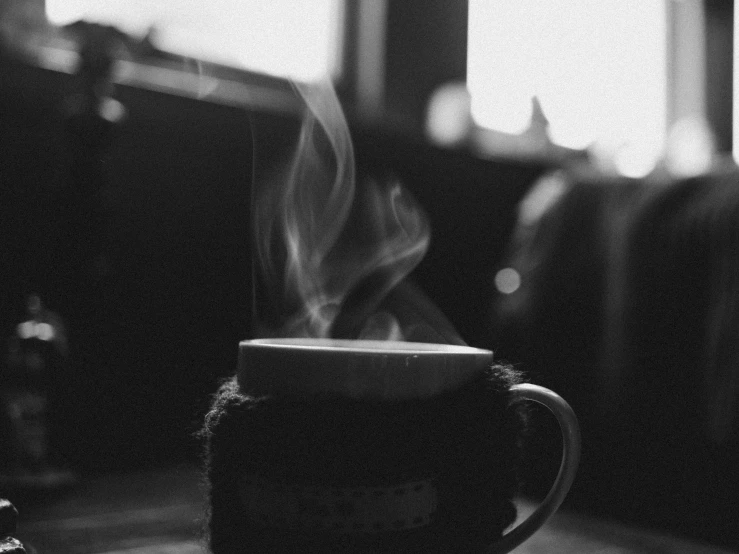 a cup of coffee sitting on top of a table, a black and white photo, by Karl Buesgen, small fire, mobile wallpaper, avatar image, cozy wallpaper