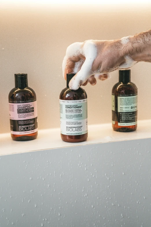 a person washing their hands with soap on a shelf, by Andries Stock, unsplash, process art, product label, bottles covered in wax, bedhead, detailed product image