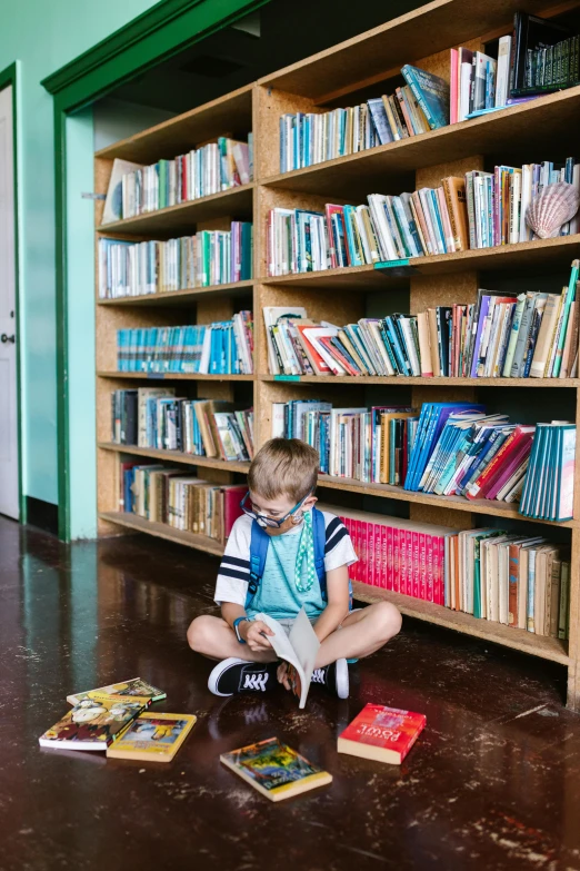 a little boy sitting on the floor in front of a bookshelf, pexels contest winner, danube school, grand library, blippi, katey truhn, with full descriptions