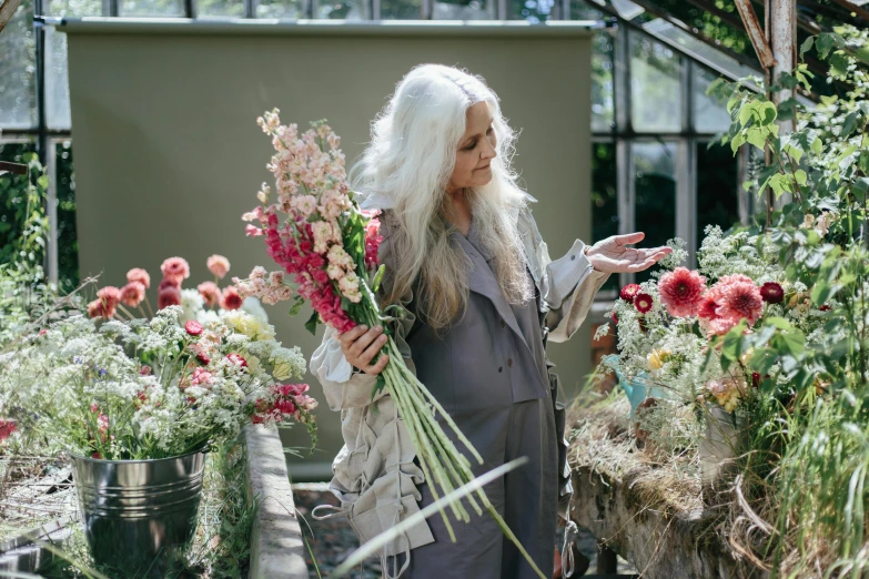 a woman holding a bunch of flowers in a greenhouse, inspired by Grethe Jürgens, unsplash, process art, silver long hair, made of dried flowers, gray haired, bouquets