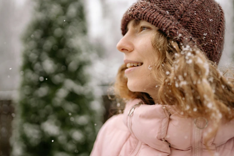 a woman in a pink jacket is outside in the snow, trending on pexels, avatar image, profile image, curly haired, close up photo