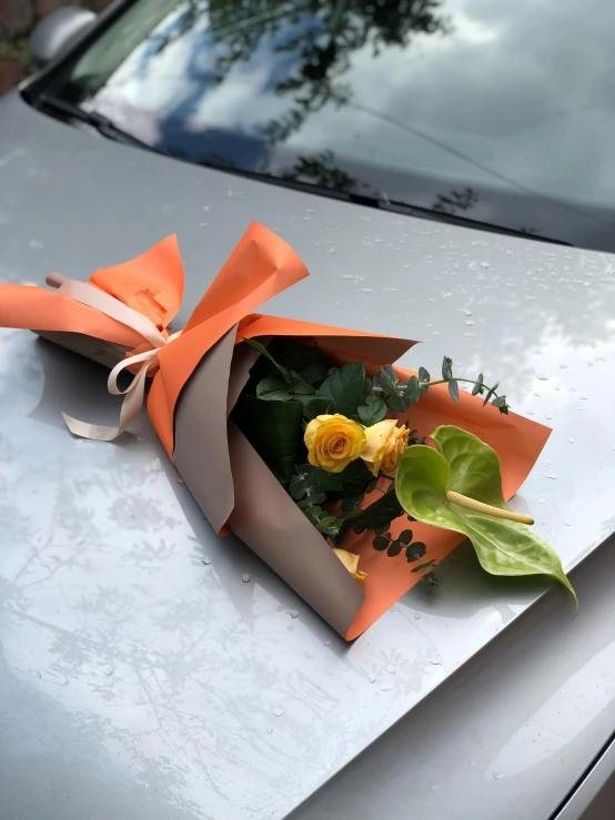 a bouquet of flowers on the hood of a car, inspired by François Boquet, unsplash, (light orange mist), wrapped, diecut, folded