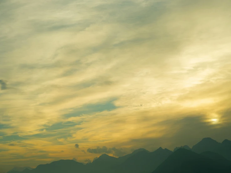 a man flying a kite on top of a lush green field, inspired by Elsa Bleda, pexels contest winner, romanticism, yellow clouds, mountainous, brown, sunset panorama