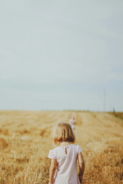 a little girl standing in the middle of a field, pexels, people walking in the distance, grain”, loosely cropped, a blond