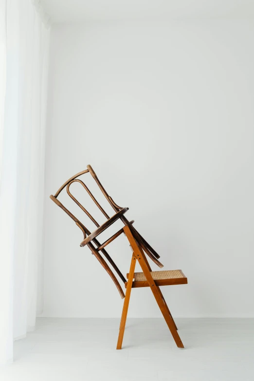 a wooden chair sitting in front of a window, inspired by Constantin Hansen, unsplash, visual art, white backdrop, folded, looking upward, antique