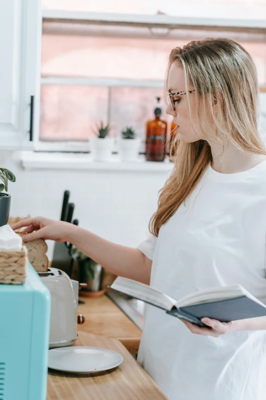 a woman sitting at a desk in front of a computer, by Nicolette Macnamara, pexels contest winner, cookbook photo, standing sideways, getting groceries, holding spell book