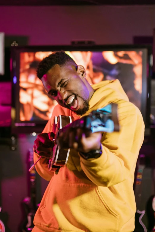 a man in a yellow hoodie playing a video game, an album cover, pexels contest winner, happening, smiling and dancing, mkbhd, holding guitars, ( ( theatrical ) )