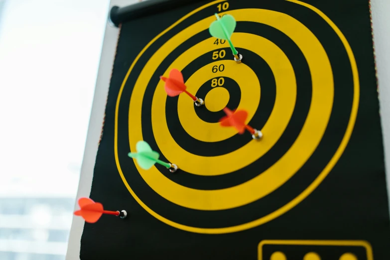 a black and yellow dart board with red and green darts, pexels contest winner, kinetic art, magnetic, instagram post, ilustration, miscellaneous objects