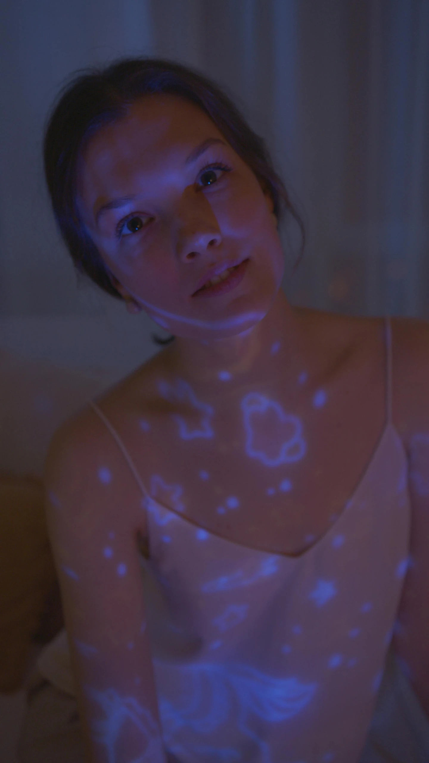 a woman sitting on top of a bed under a blue light, markings on her face, star map, voronoi, lumen global illumination