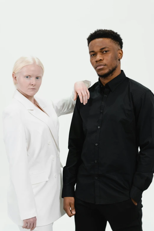 a man and a woman standing next to each other, white and black clothing, with a white complexion, ready to model, wearing a black shirt