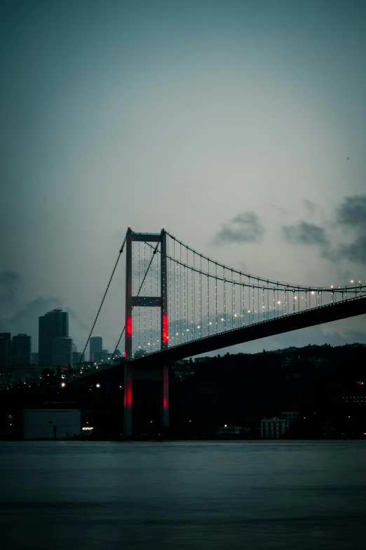 a bridge over a body of water with a city in the background, inspired by Elsa Bleda, pexels contest winner, hurufiyya, turkish and russian, 2 5 6 x 2 5 6, humid evening, grayish