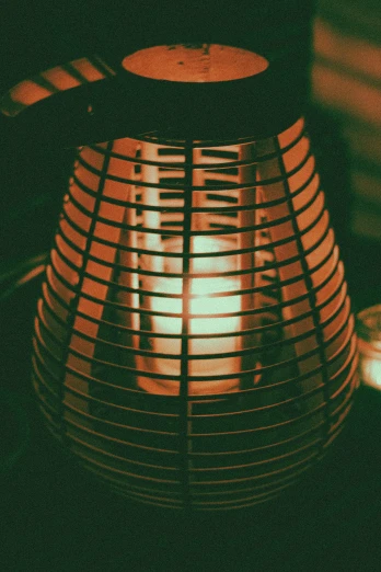 a close up of a lamp on a table, an album cover, unsplash, glowing heating coils, lantern candle, tiki, cage