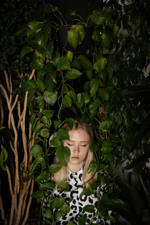 a woman in a black and white dress standing in front of a tree, inspired by Elsa Bleda, trending on pexels, surrealism, verdant plants green wall, elle fanning at night, made of leaves, portrait of kim petras