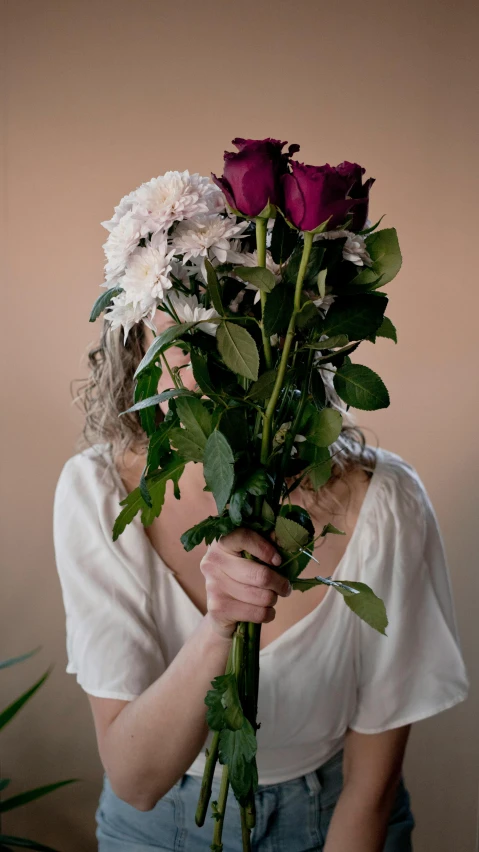 a woman holding a bunch of flowers in front of her face, an album cover, inspired by Anna Füssli, natural point rose', pose 1 of 1 6, chrysanthemum and hyacinth, over the shoulder