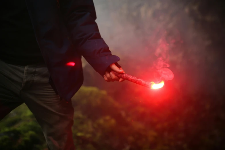 a man holding a red light in his hand, pexels contest winner, auto-destructive art, hiking cane, wielding a fireball, forest ritual, volcanic