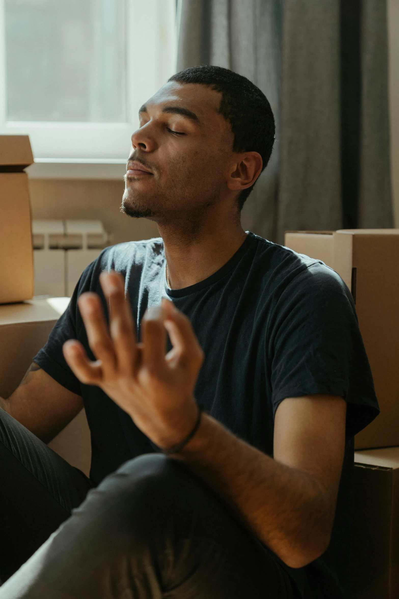 a man sitting on the floor surrounded by boxes, pexels contest winner, renaissance, praying meditating, his palms are sweaty, black man, shrugging arms