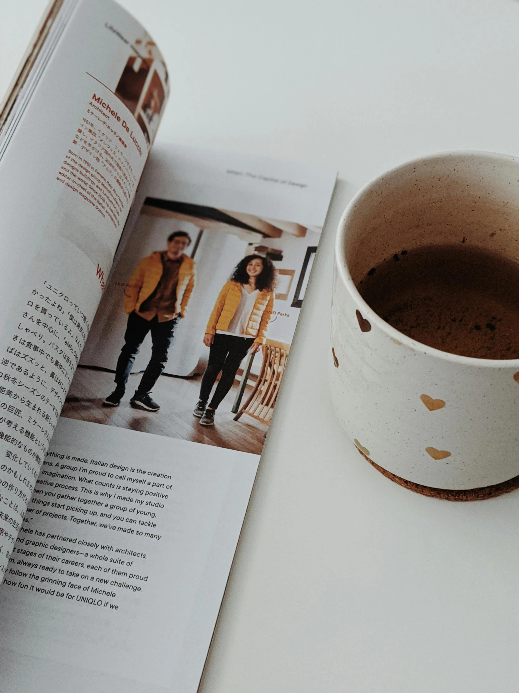 a cup of coffee and a book on a table, by Lucia Peka, happening, cover of a magazine, golden chinese text, casually dressed, handmade pottery