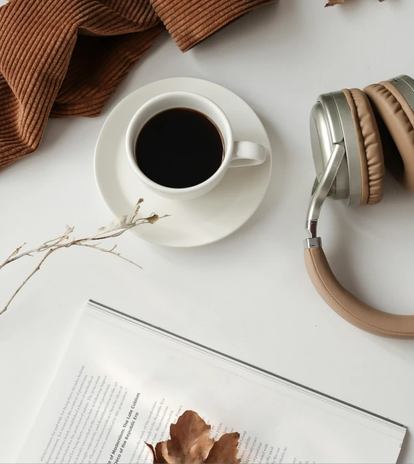 a cup of coffee and headphones on a table, a still life, trending on pexels, minimalism, brown and white color scheme, multiple stories, realistic »
