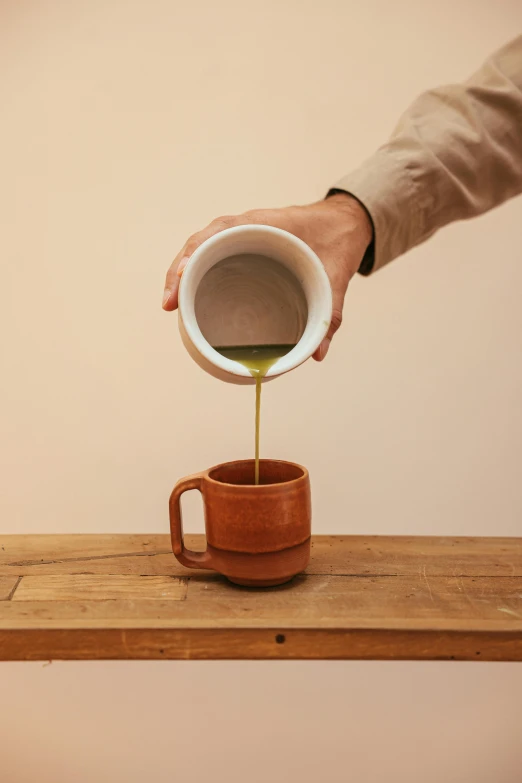 a person pouring something into a cup on a table, inspired by Ceferí Olivé, cedar, detailed product shot, kano tan'yu, growing