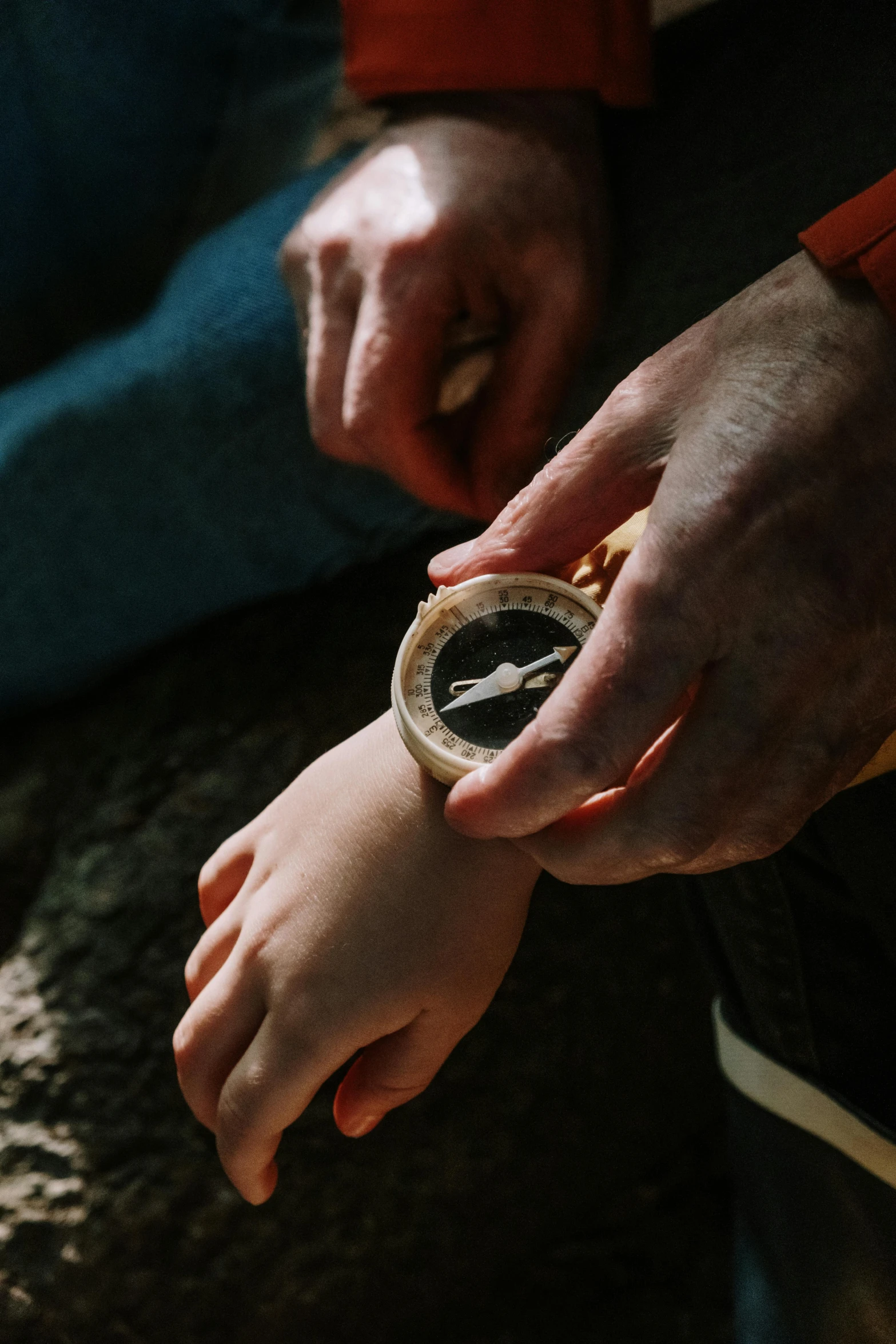 a close up of a person holding a watch, by Daren Bader, father with child, compass, wooden, humans exploring