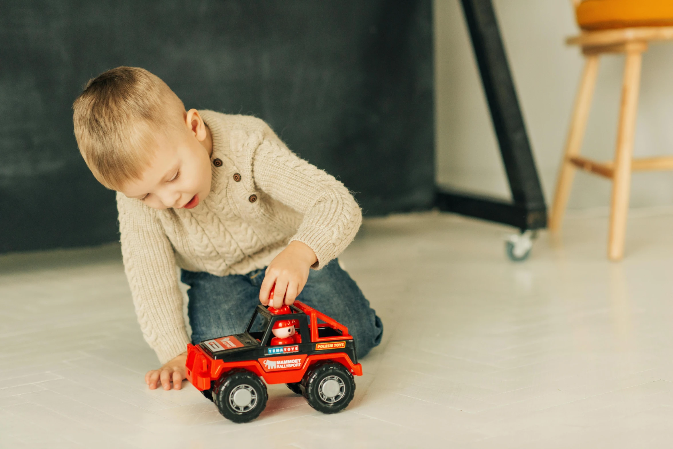 a young boy playing with a toy truck, pexels contest winner, red and black colour scheme, hugging his knees, full product shot, a small