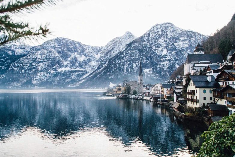 a large body of water surrounded by mountains, a photo, by Sebastian Spreng, pexels contest winner, quaint village, winter vibes, 🚿🗝📝