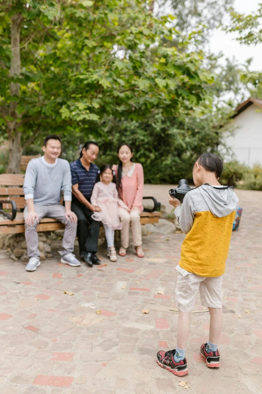 a group of people sitting on top of a wooden bench, a picture, holding a camera, of a family standing in a park, steve zheng, at home